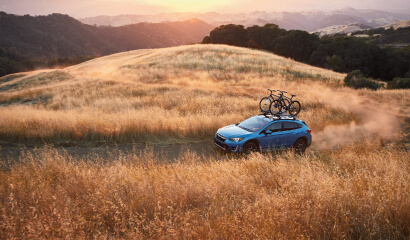 A 2023 Crosstrek Hybrid driving on a dirt road.