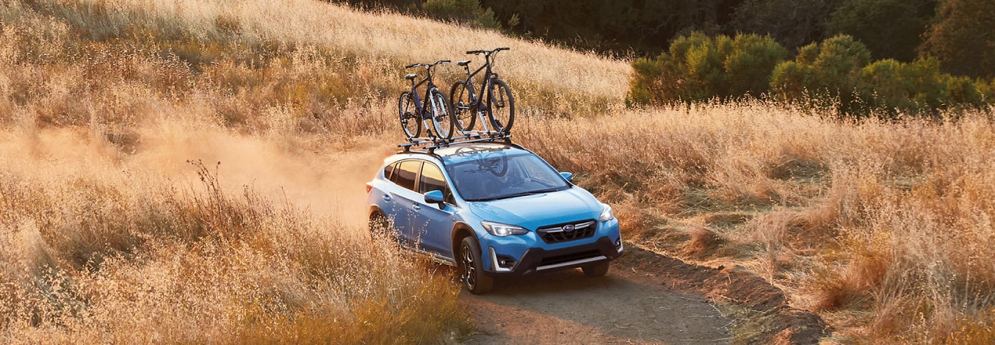 A 2023 Crosstrek Hybrid driving on a dirt road.