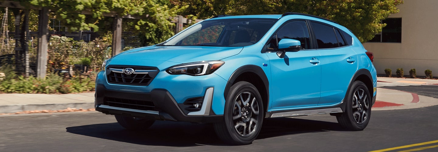 A 2023 Crosstrek Hybrid driving on a city street.