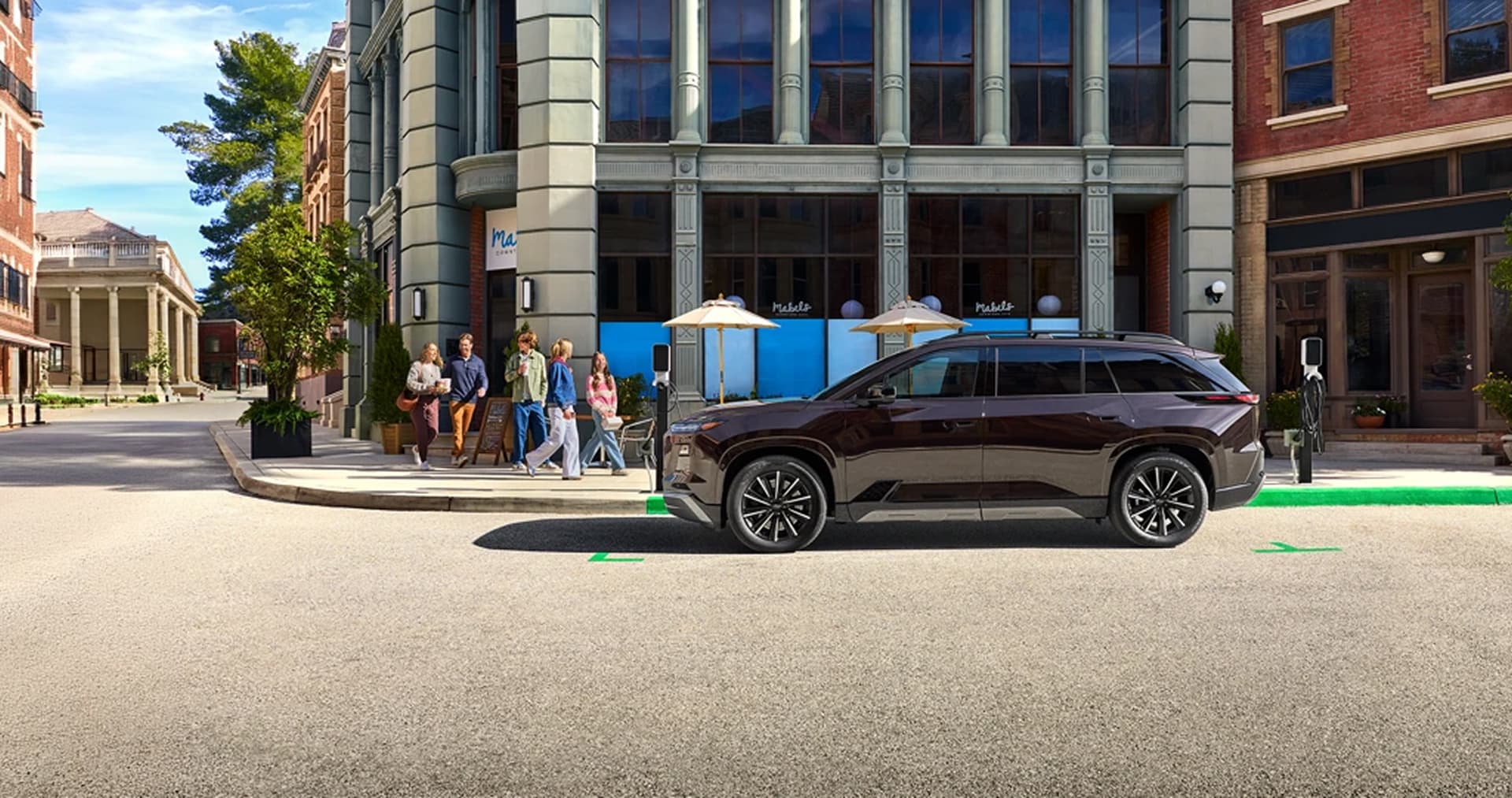 2027 Subaru EV SUV parked at curb outside of urban coffee shop.