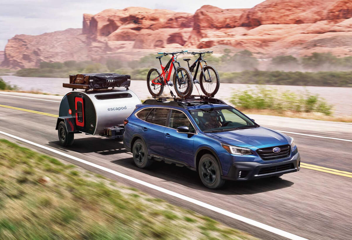 A 2022 Subaru Outback hauling a camping trailer through the desert.