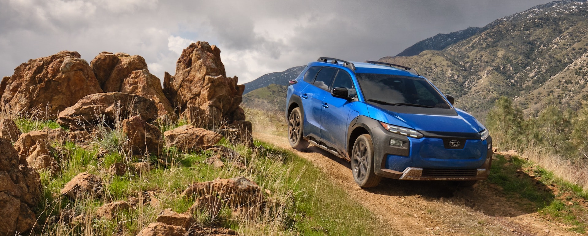 A 2026 Subaru Trailseeker in blue drives down an arid hill.