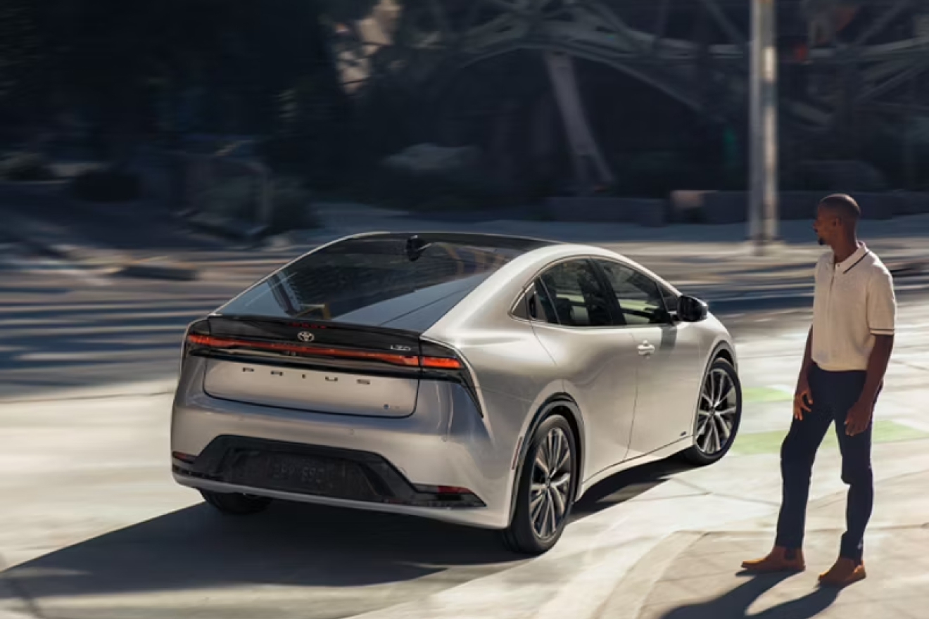 2027 Prius near a curbside with a person is walking towards it