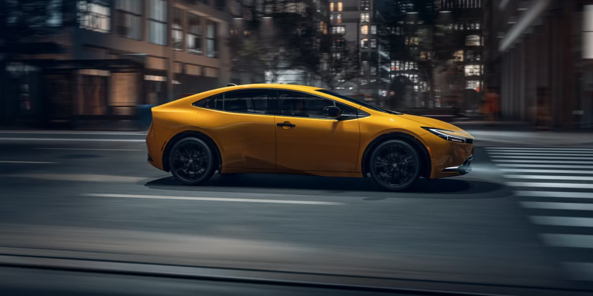 2027 Prius in Karashi color driving in city toward the right