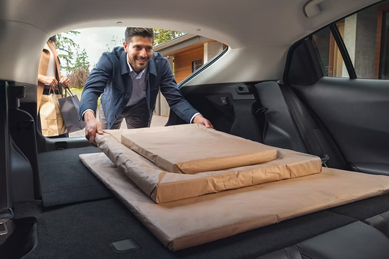 Interior shot of folded down back seats and a man loading large items over them