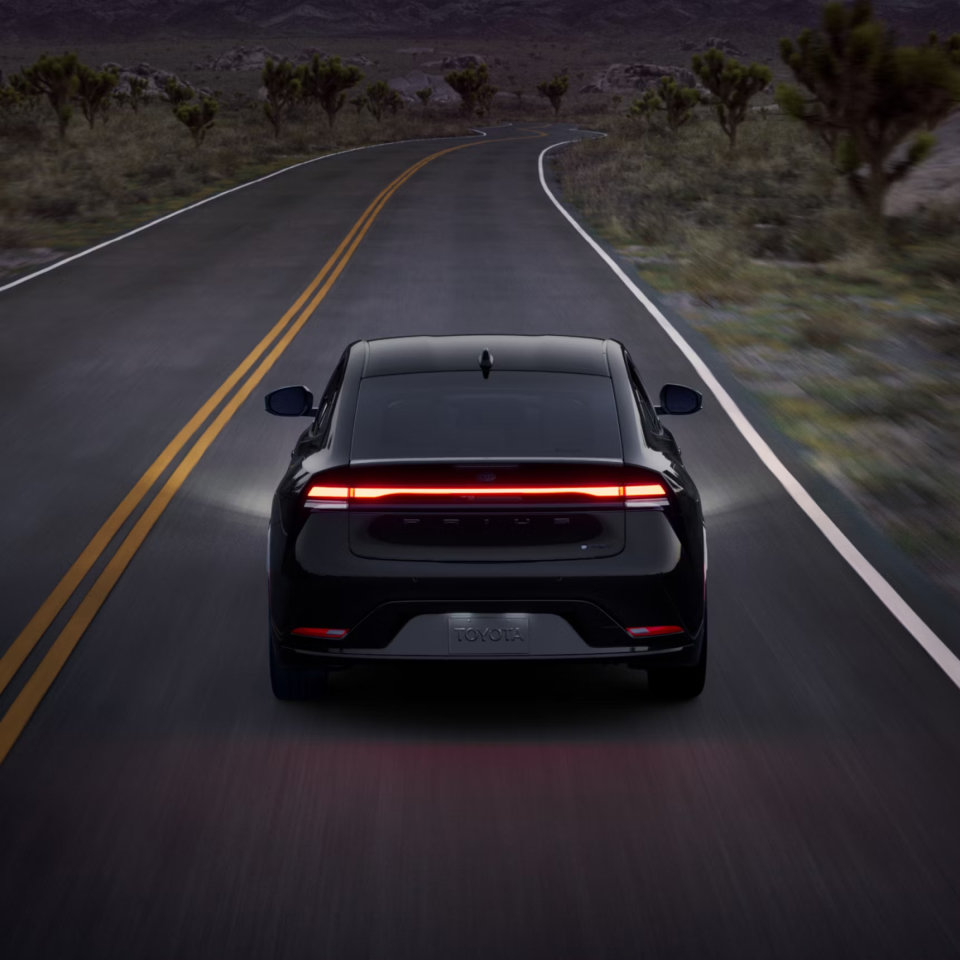 2027 Prius Plug-in Hybrid driving away from viewer at night on a desolate road
