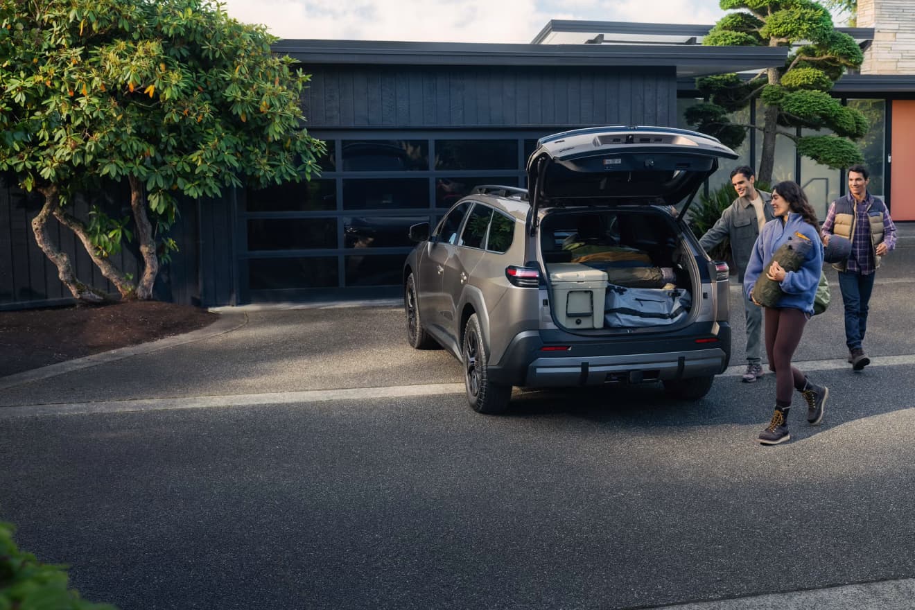People loading gear into the open rear cargo area of a 2027 Toyota bZ Woodland
