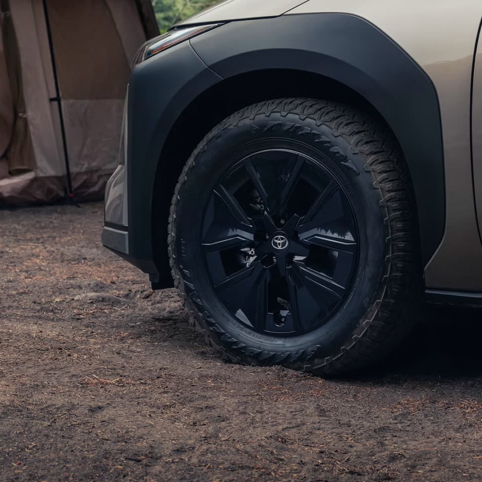 Close-up of the 2027 Toyota bZ Woodland front wheel and tire on a dirt trail
