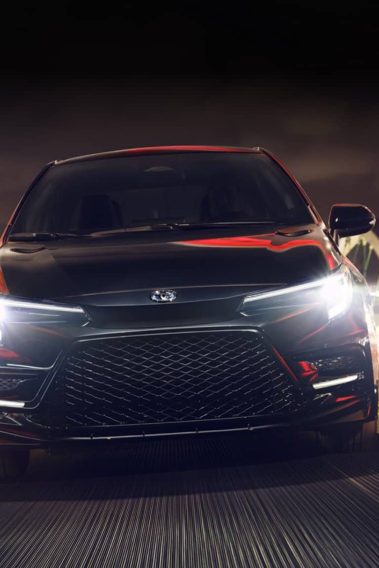 Front of Toyota sedan with headlights on