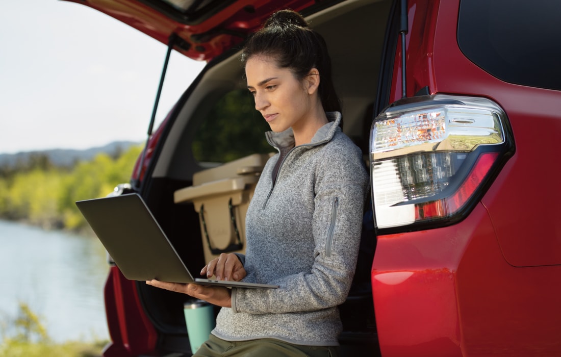 woman with a laptop near the tailgate of a Toyota
