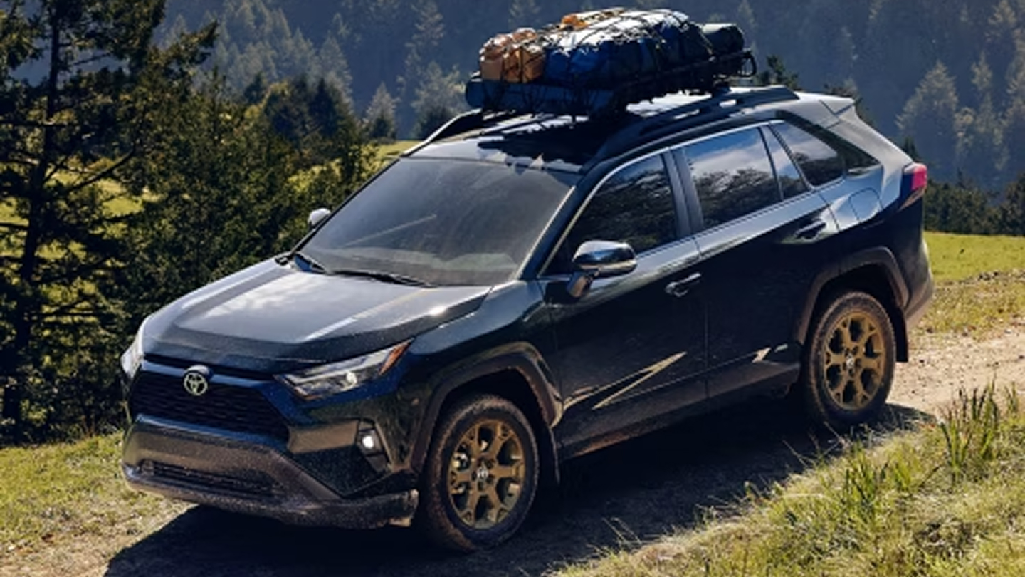 RaV4 Hybrid with cargo on its roof rack driving over a scenic mountain trail