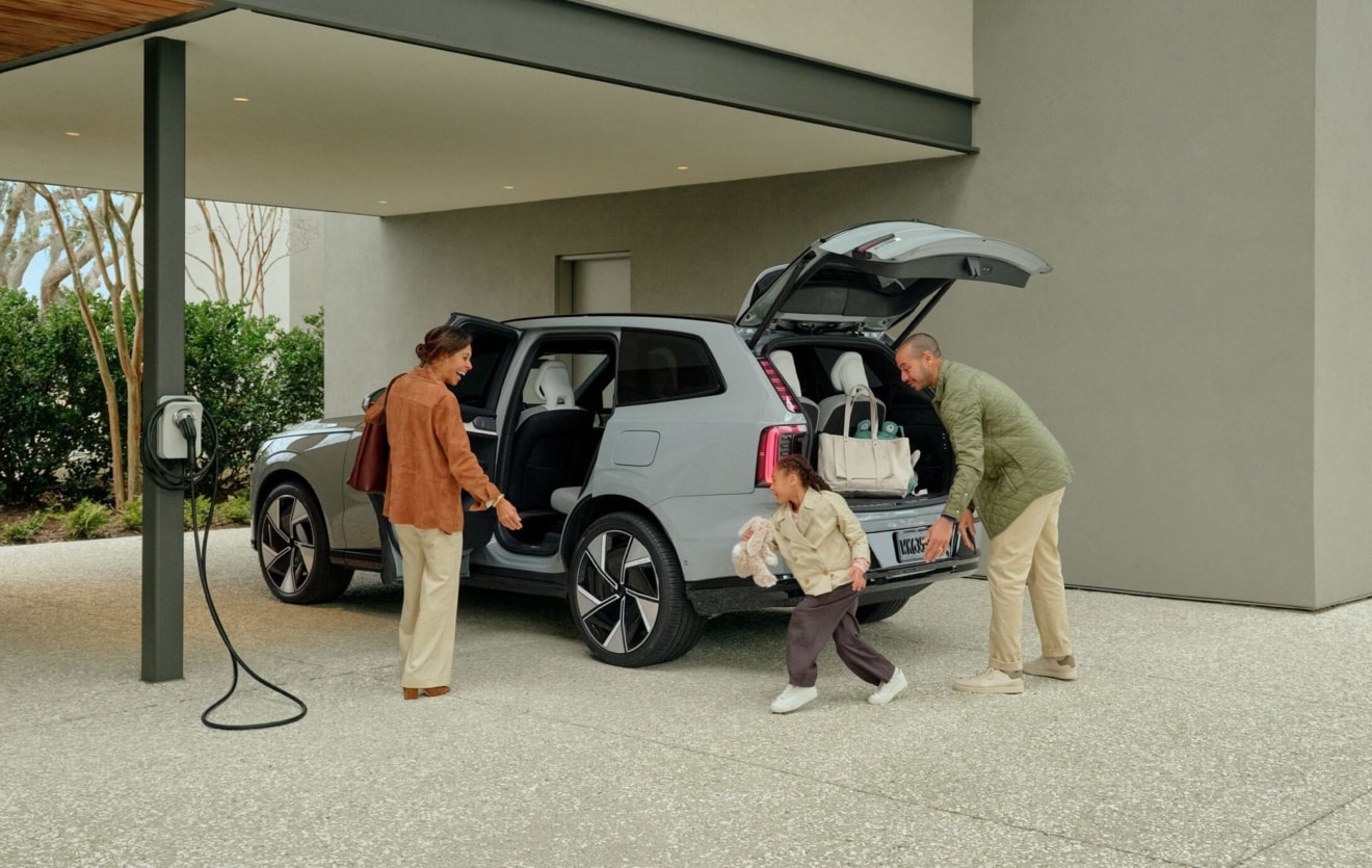 family loading a Volvo SUV near a home charger
