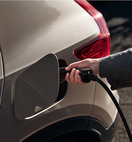 hand connecting a charger to a Volvo vehicle