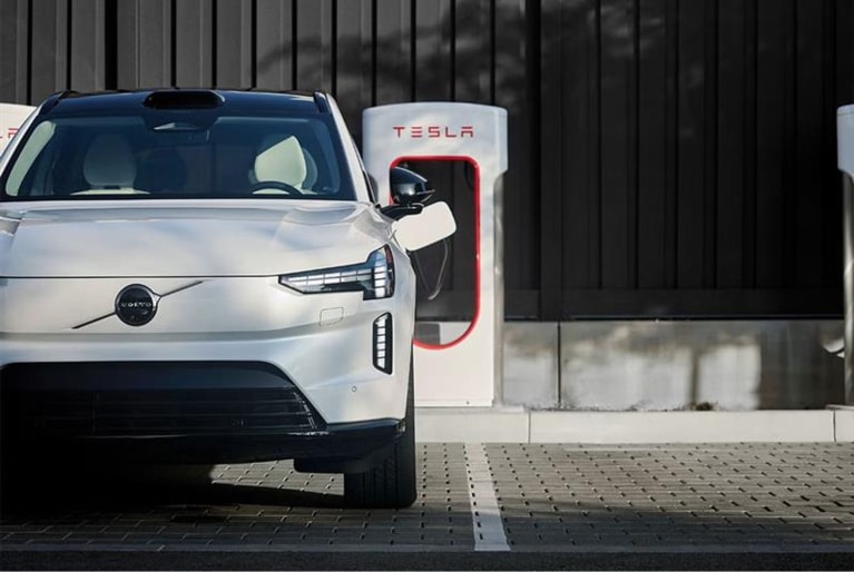 an electric Volvo SUV charging at a Tesla NACS charger