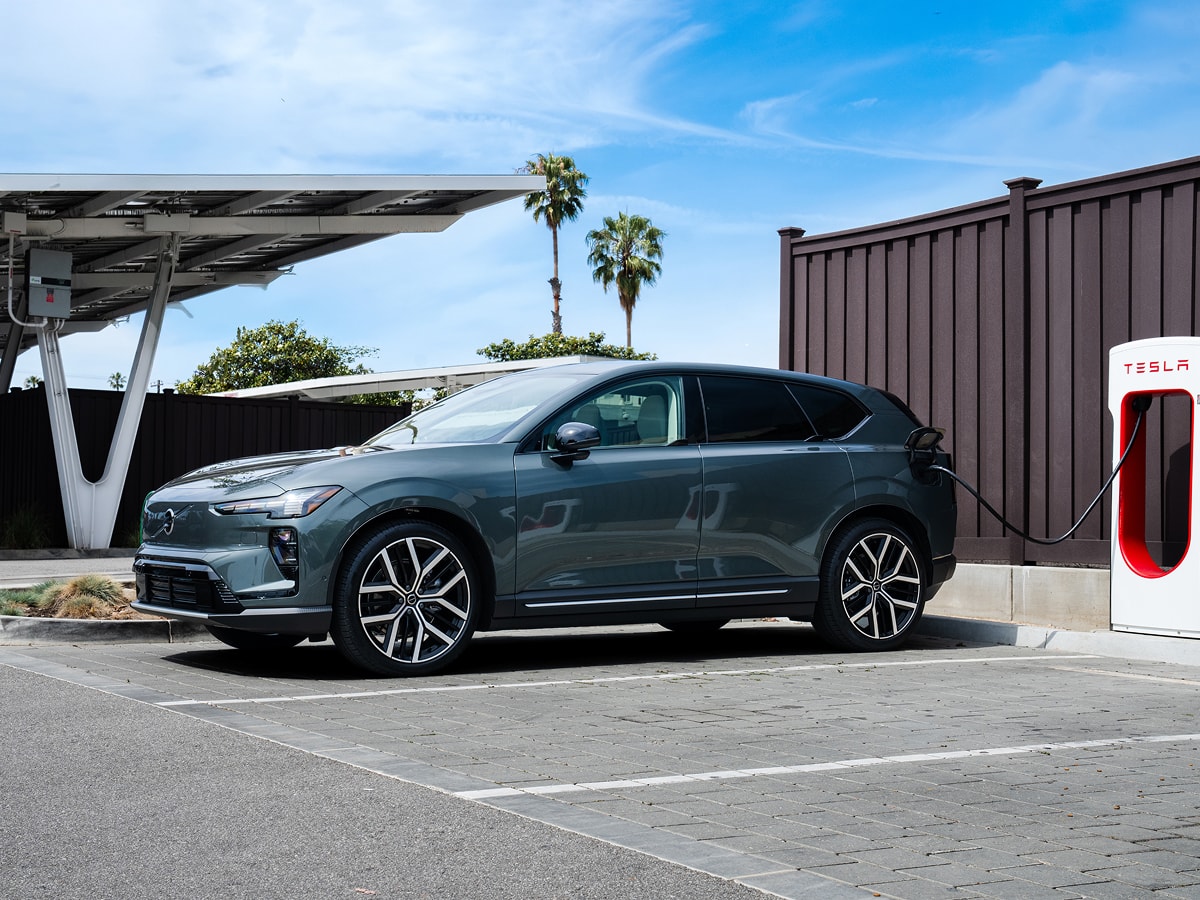 Volvo EX60 charging in a lot of Tesla Superchargers